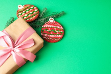 Photo of Saint Nicholas day. Gift box, fir branch and gingerbread cookies on green background, flat lay. Space for text