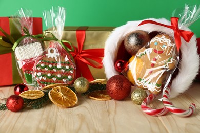 Photo of Happy Saint Nicholas day. Different festive decor, gift boxes and cookies on wooden table against green background, closeup