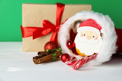 Photo of Happy Saint Nicholas day. Baubles, gift box and sweets on white wooden table against green background, closeup