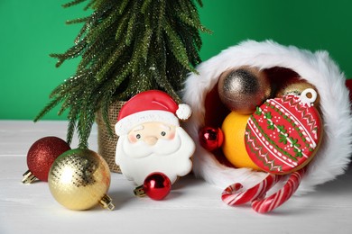Photo of Happy Saint Nicholas day. Different festive decor and sweets on white wooden table against green background, closeup