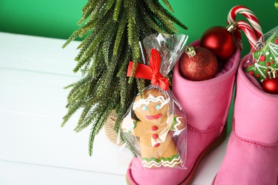 Photo of Happy Saint Nicholas day. Boots with festive decor and cookies on white wooden table, closeup. Space for text