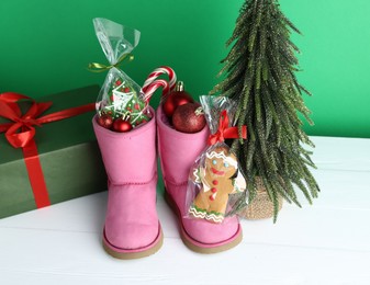 Photo of Happy Saint Nicholas day. Boots with festive decor, sweets and gift box on white wooden table