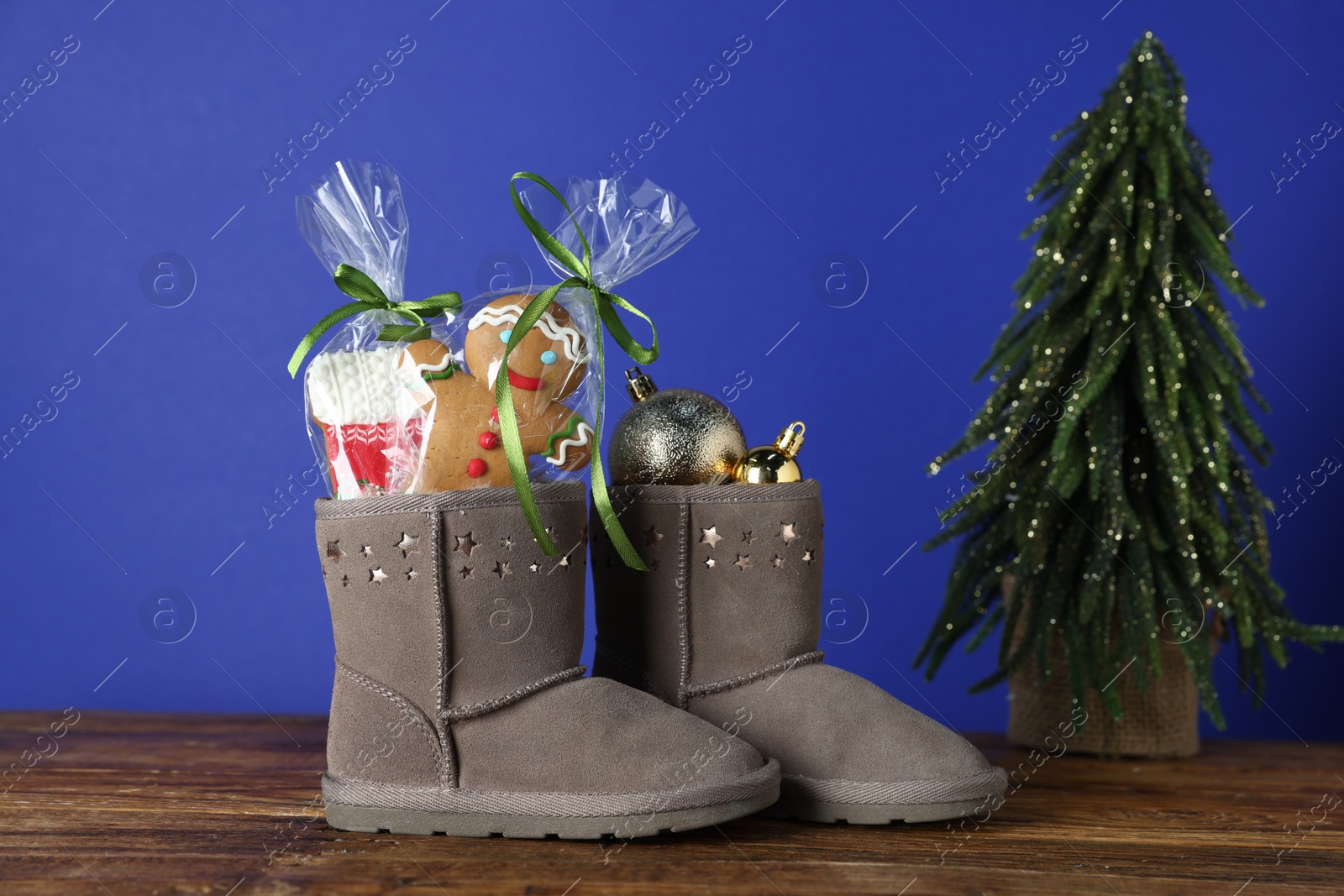 Happy Saint Nicholas day. Boots with cookies and festive decor on wooden table against blue background Photo of Happy Saint Nicholas day. Boots with cookies and festive decor on wooden table against blue background