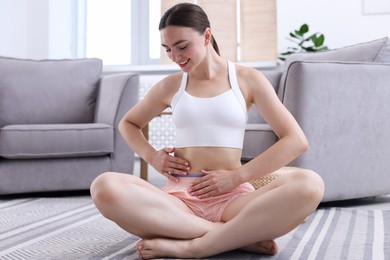 Photo of Happy woman with flat belly on floor at home