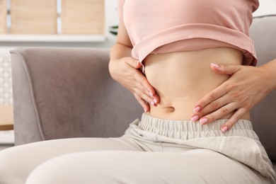 Photo of Woman with flat belly on sofa at home, closeup