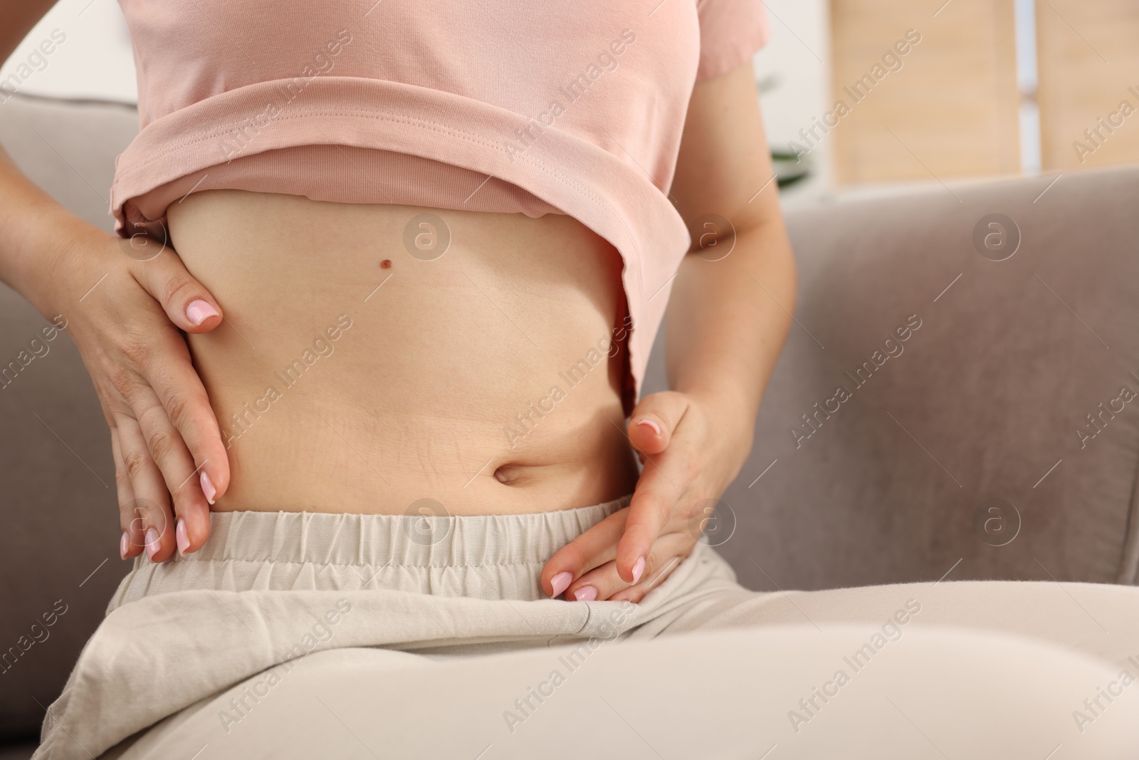 Woman with flat belly on sofa at home, closeup Photo of Woman with flat belly on sofa at home, closeup