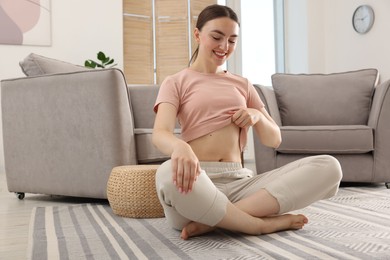 Photo of Happy woman with flat belly on floor at home