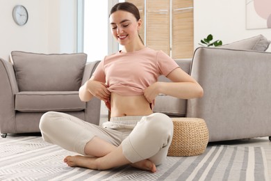 Photo of Happy woman with flat belly on floor at home