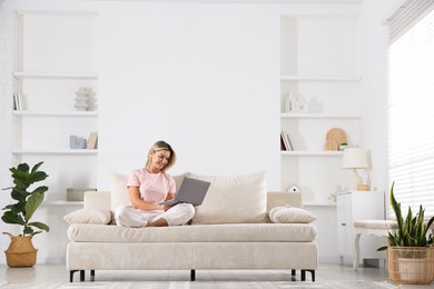 Photo of Beautiful woman using laptop on sofa at home