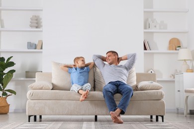 Photo of Father and his son relaxing on sofa at home