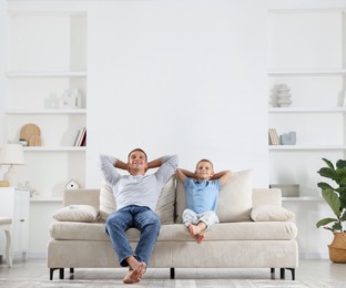 Photo of Father and his son relaxing on sofa at home