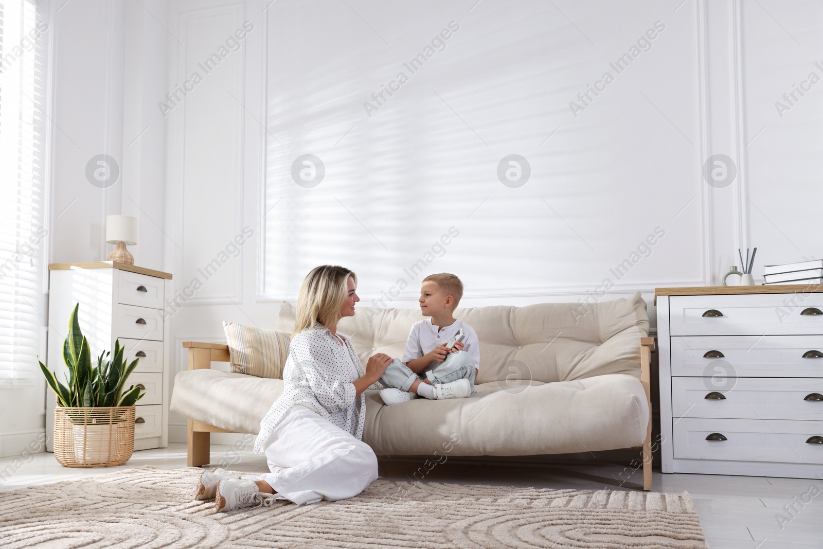 Woman and her son with air conditioner remote control on sofa at home Photo of Woman and her son with air conditioner remote control on sofa at home