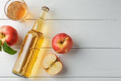 Photo of Delicious cider in glass bottle and apples on white wooden table, flat lay. Space for text