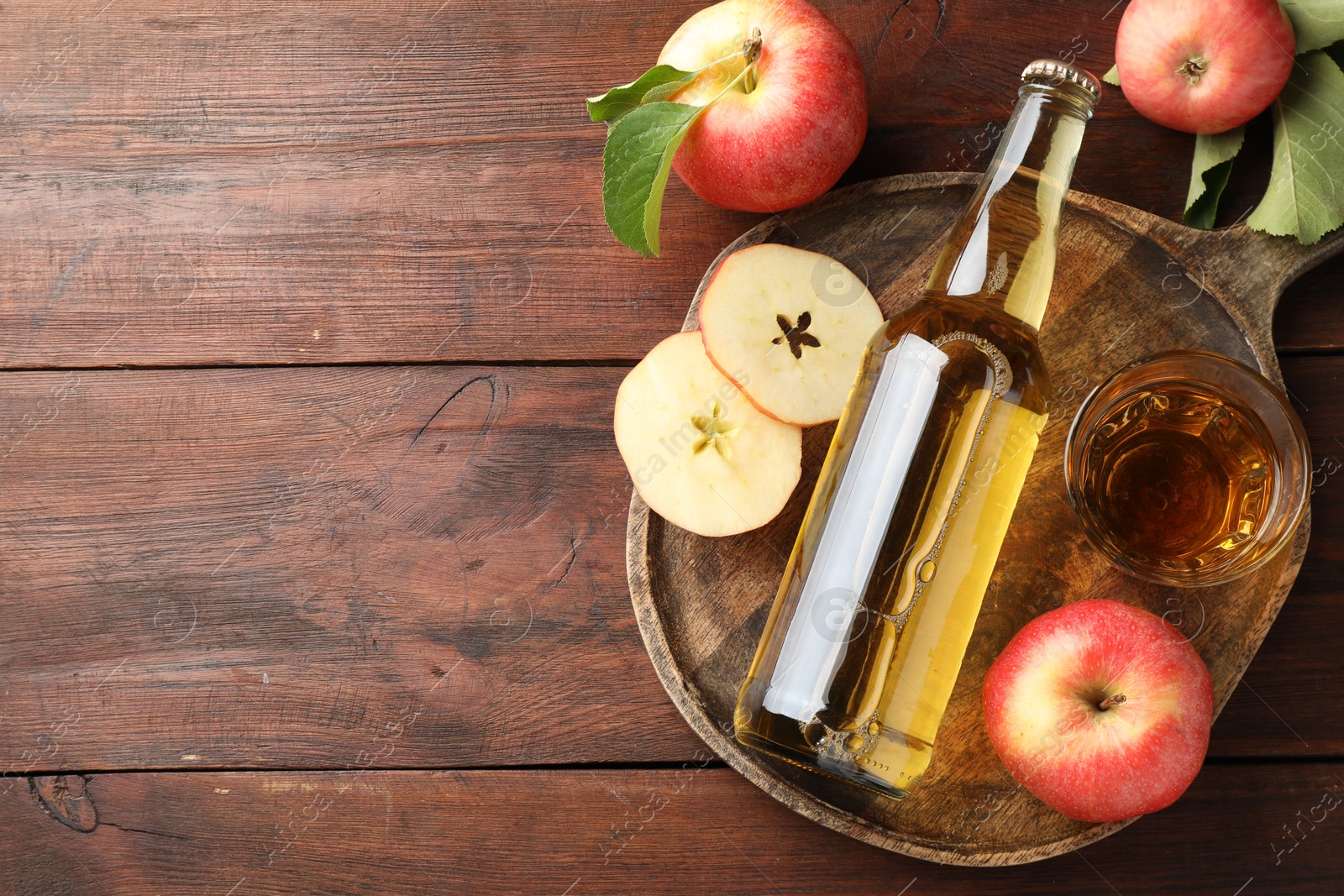 Photo of Delicious cider in bottle, glass and apples on wooden table, flat lay. Space for text