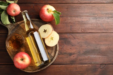 Photo of Delicious cider in bottle, glass and apples on wooden table, flat lay. Space for text