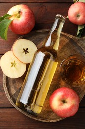 Photo of Delicious cider in bottle, glass and apples on wooden table, flat lay