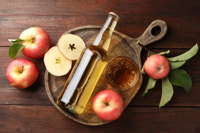 Photo of Delicious cider in bottle, glass and apples with green leaves on wooden table, flat lay