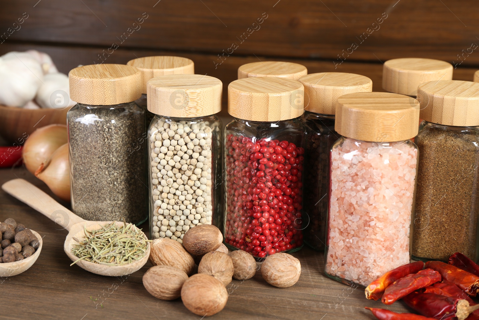 Photo of Different spices and jars on wooden table, closeup