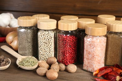 Photo of Different spices and jars on wooden table, closeup