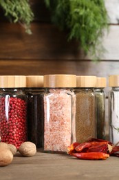 Photo of Different spices and jars on wooden table, closeup