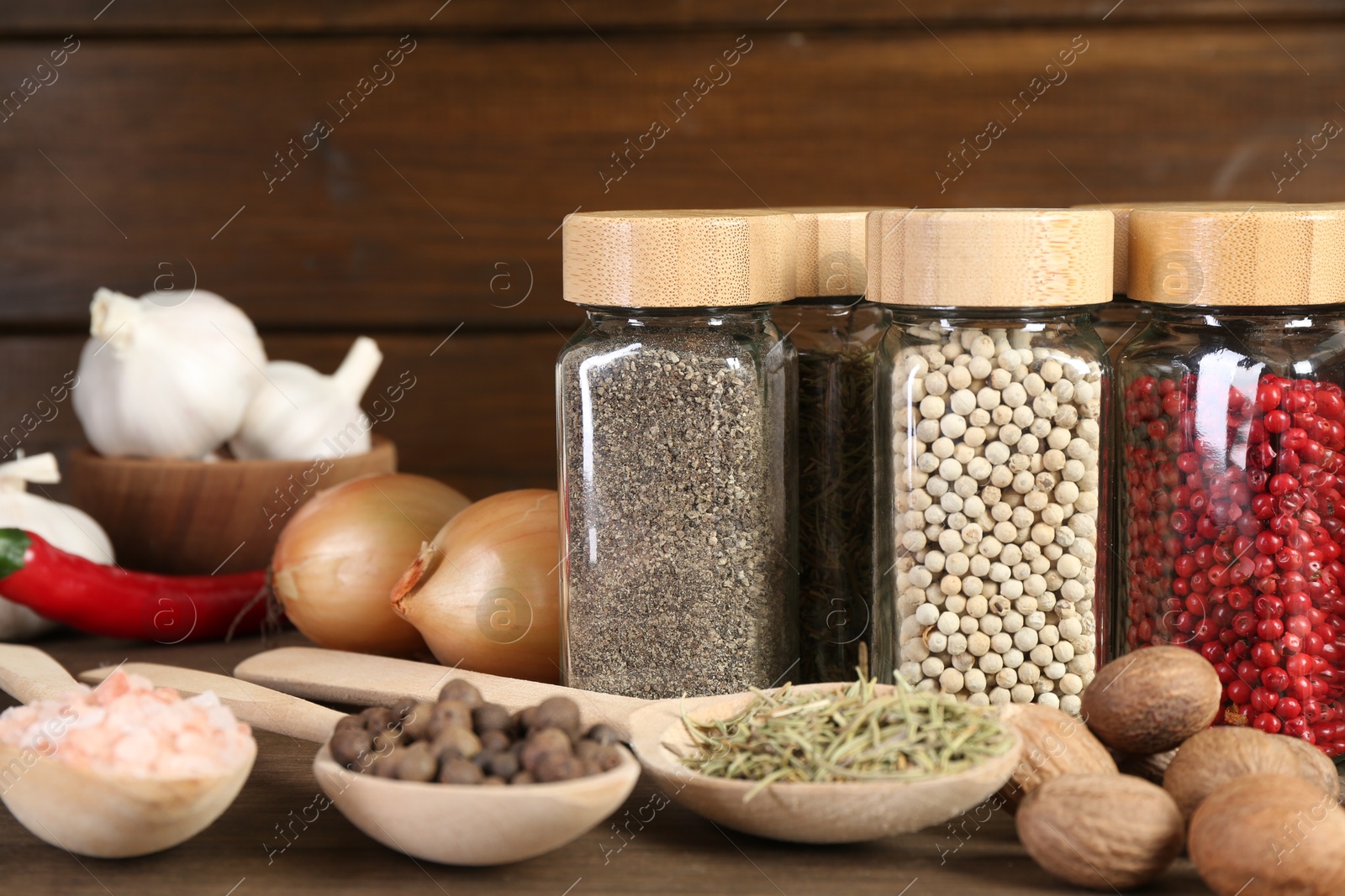 Photo of Different spices and jars on wooden table, closeup