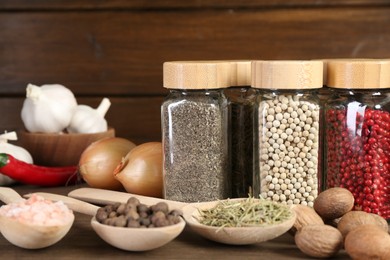 Photo of Different spices and jars on wooden table, closeup