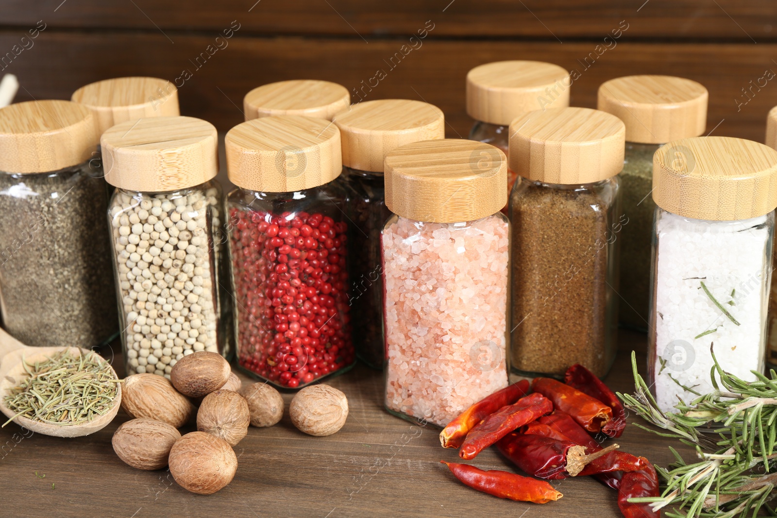 Photo of Different spices and jars on wooden table, closeup