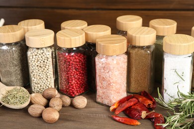Photo of Different spices and jars on wooden table, closeup