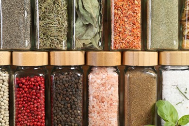 Photo of Different spices and jars on wooden background, closeup