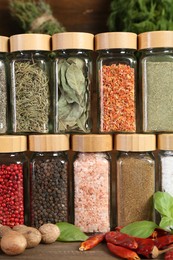 Photo of Different spices and jars on wooden table, closeup