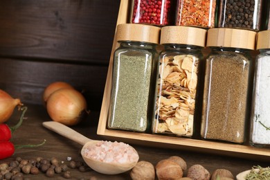 Photo of Different spices and jars on wooden table, closeup