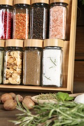 Photo of Different spices and jars on wooden table, closeup