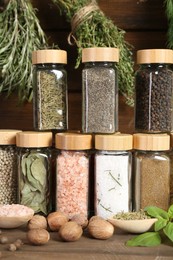 Photo of Different spices and jars on wooden table, closeup