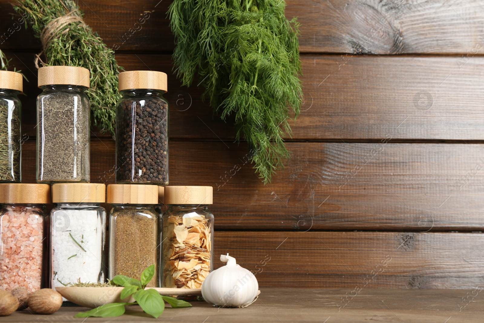 Photo of Different spices and jars on wooden table. Space for text