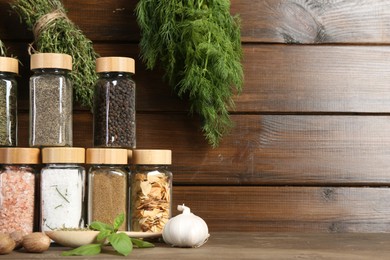 Photo of Different spices and jars on wooden table. Space for text