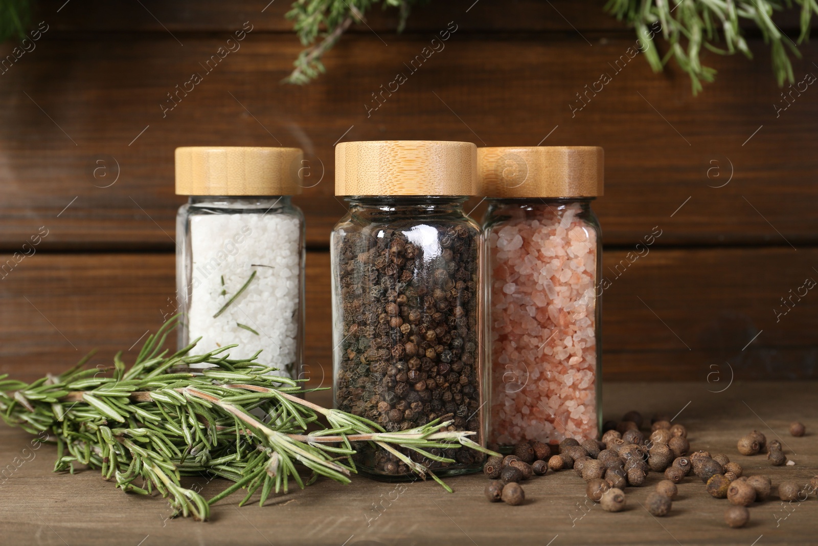 Photo of Different spices and jars on wooden table, closeup