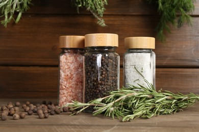 Photo of Different spices and jars on wooden table, closeup