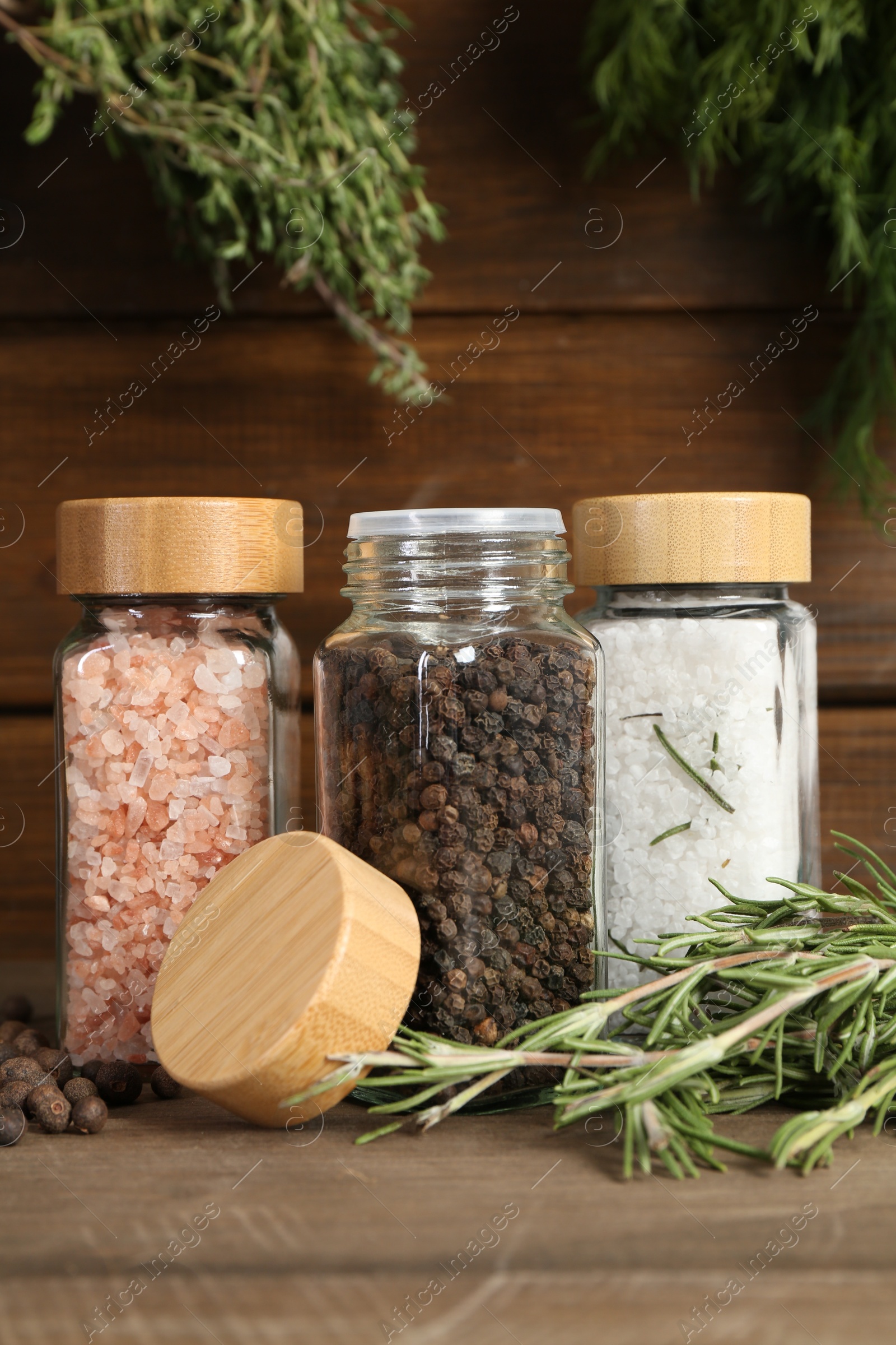 Photo of Different spices and jars on wooden table, closeup