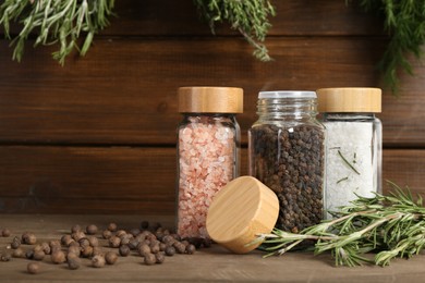Photo of Different spices and jars on wooden table, closeup. Space for text