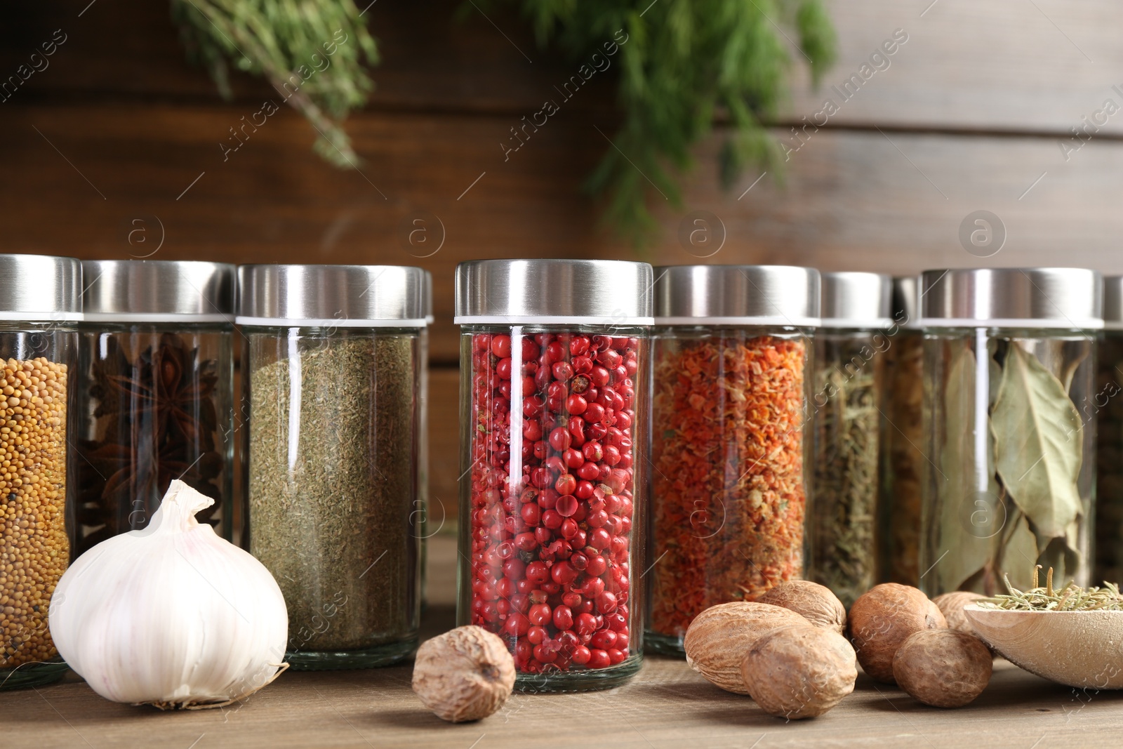 Photo of Different spices and jars on wooden table, closeup
