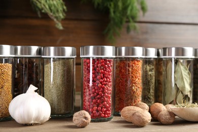 Photo of Different spices and jars on wooden table, closeup
