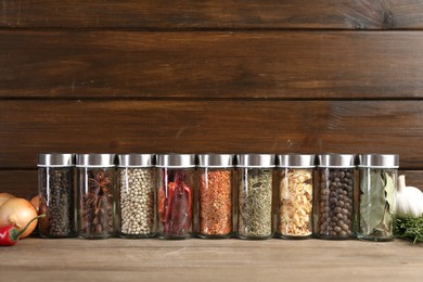 Photo of Different spices and jars on wooden table. Space for text