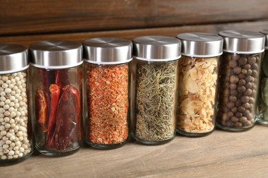 Photo of Different spices and jars on wooden table, closeup