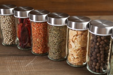 Photo of Different spices and jars on wooden table, closeup