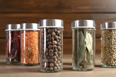 Photo of Different spices and jars on wooden table, closeup