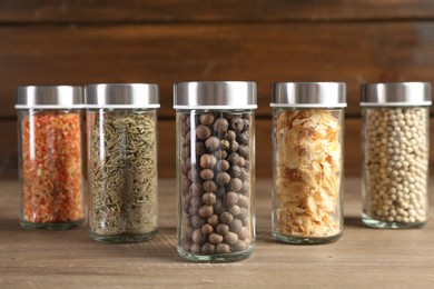 Photo of Different spices and jars on wooden table, closeup