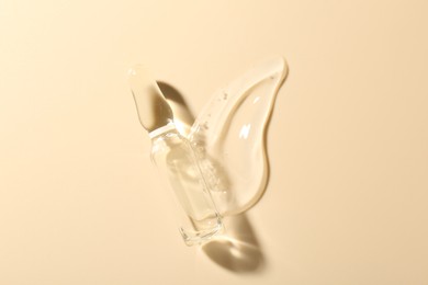 Photo of Glass ampoule with cosmetic product and sample on beige background, top view
