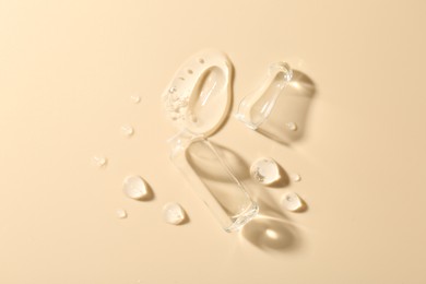 Photo of Broken glass ampoule and cosmetic product on beige background, top view