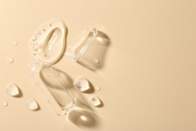 Photo of Broken glass ampoule and cosmetic product on beige background, top view