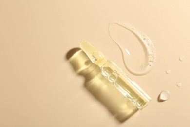 Photo of Glass ampoule with cosmetic product and sample on beige background, top view. Space for text
